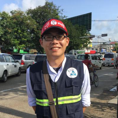 Mu-Lung wearing glasses smiling with traffic behind him
